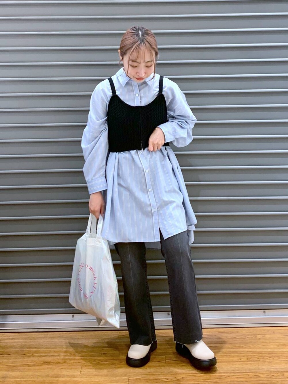 ブラック系のニット/セーター、ブルー系のチュニック、ホワイト系のトートバッグを着用したレディースの春コーディネートの4枚目の写真