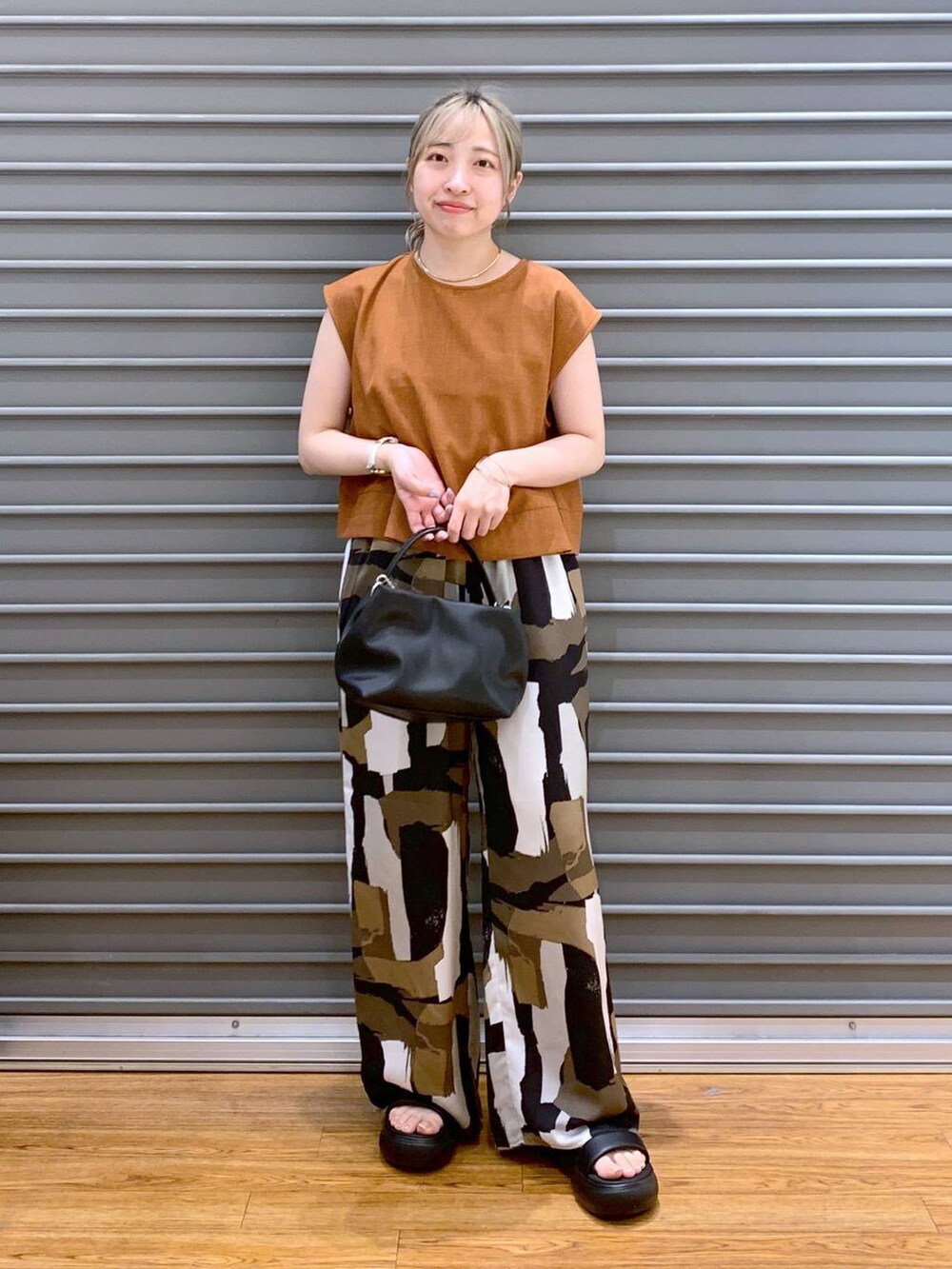 ブラック系のサンダル、オレンジ系のシャツ/ブラウス、ブラック系のショルダーバッグを着用したレディースの夏コーディネートの6枚目の写真