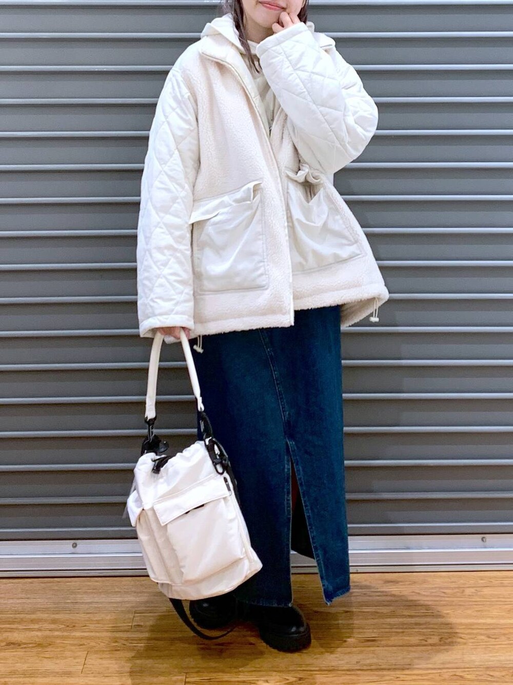 ホワイト系のショルダーバッグ、ブルー系のジャンパースカート、ブラック系のブーツを着用したレディースの冬コーディネートの6枚目の写真