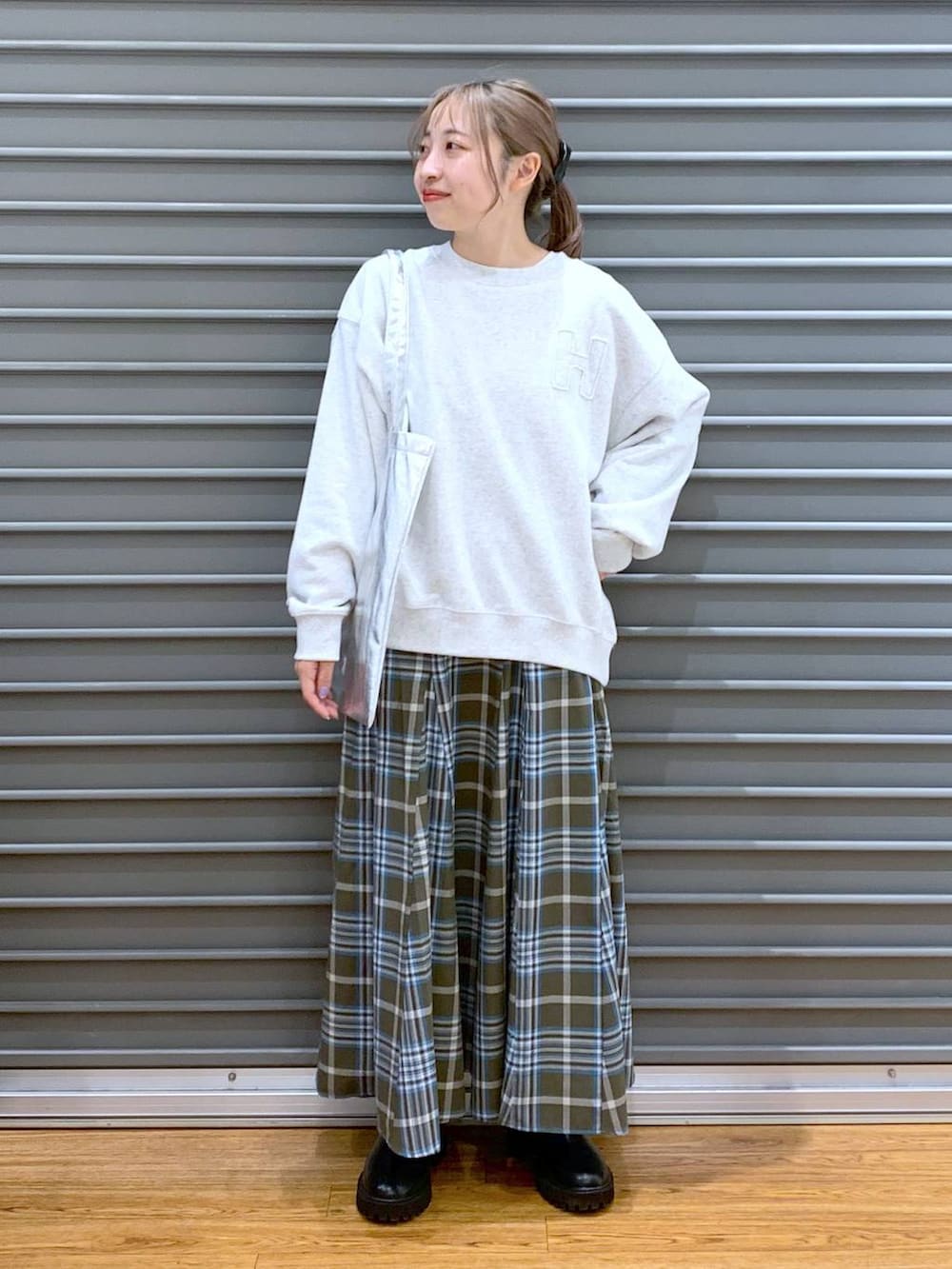 シルバー系のトートバッグ、ブラック系のブーツ、グリーン系のスカートを着用したレディースの冬コーディネートの5枚目の写真