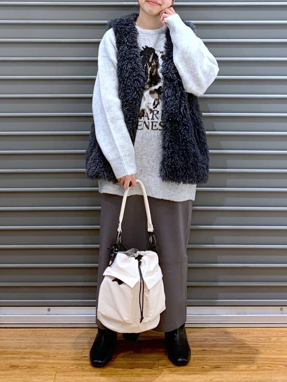 ホワイト系のショルダーバッグ、グレー系のスカート、ブラック系のブーツを着用したレディースの冬コーディネートの6枚目の写真