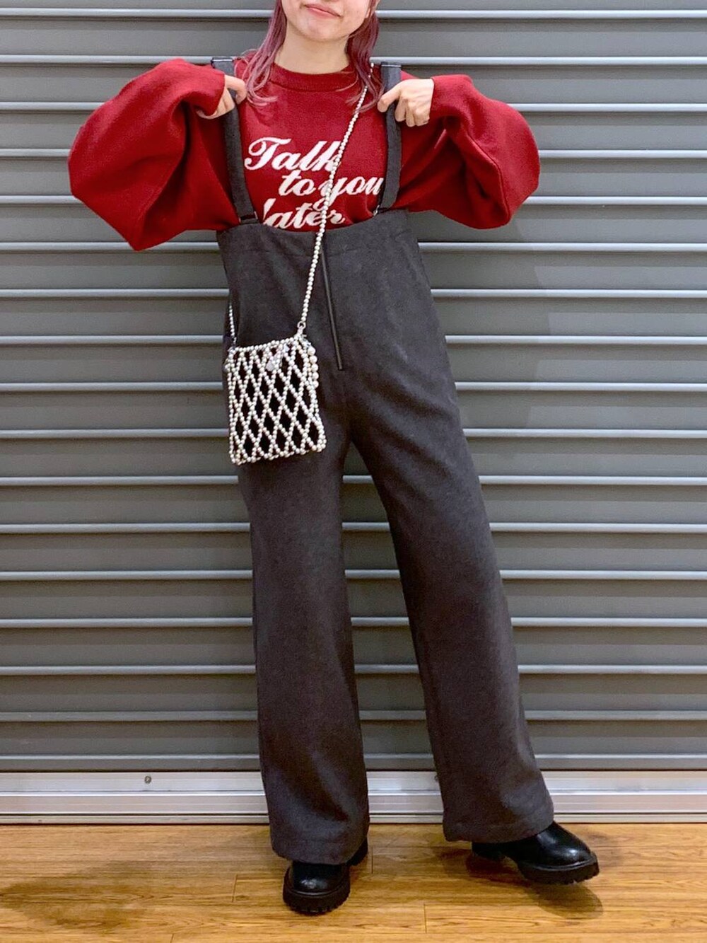 シルバー系のショルダーバッグ、レッド系のニット/セーター、ブラック系のブーツを着用したレディースの冬コーディネートの5枚目の写真