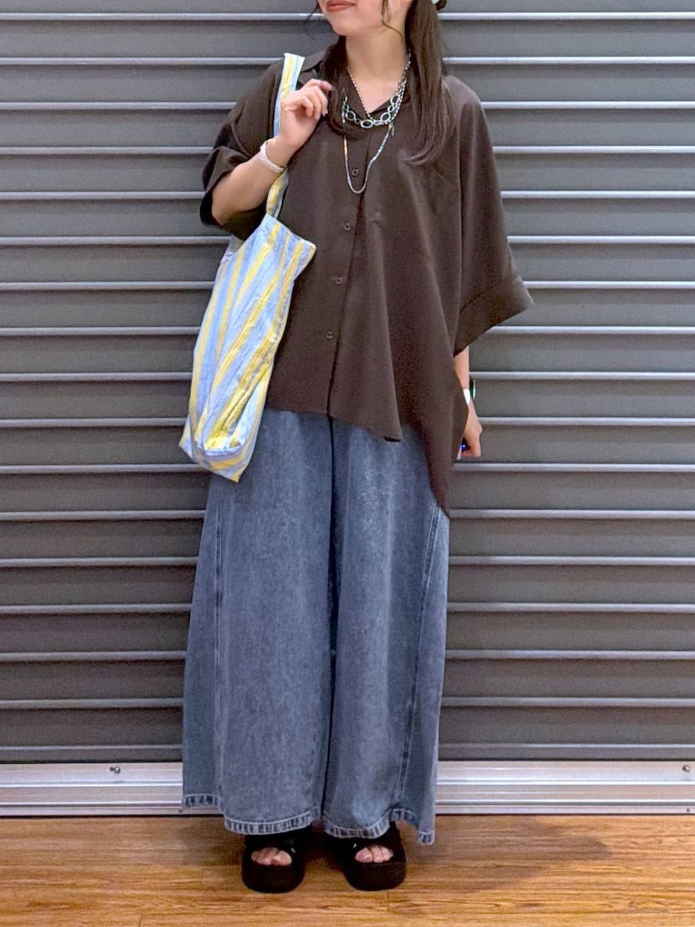 ブルー系のトートバッグ、ブラウン系のシャツ/ブラウス、ブラック系のサンダルを着用したレディースの夏コーディネートの5枚目の写真