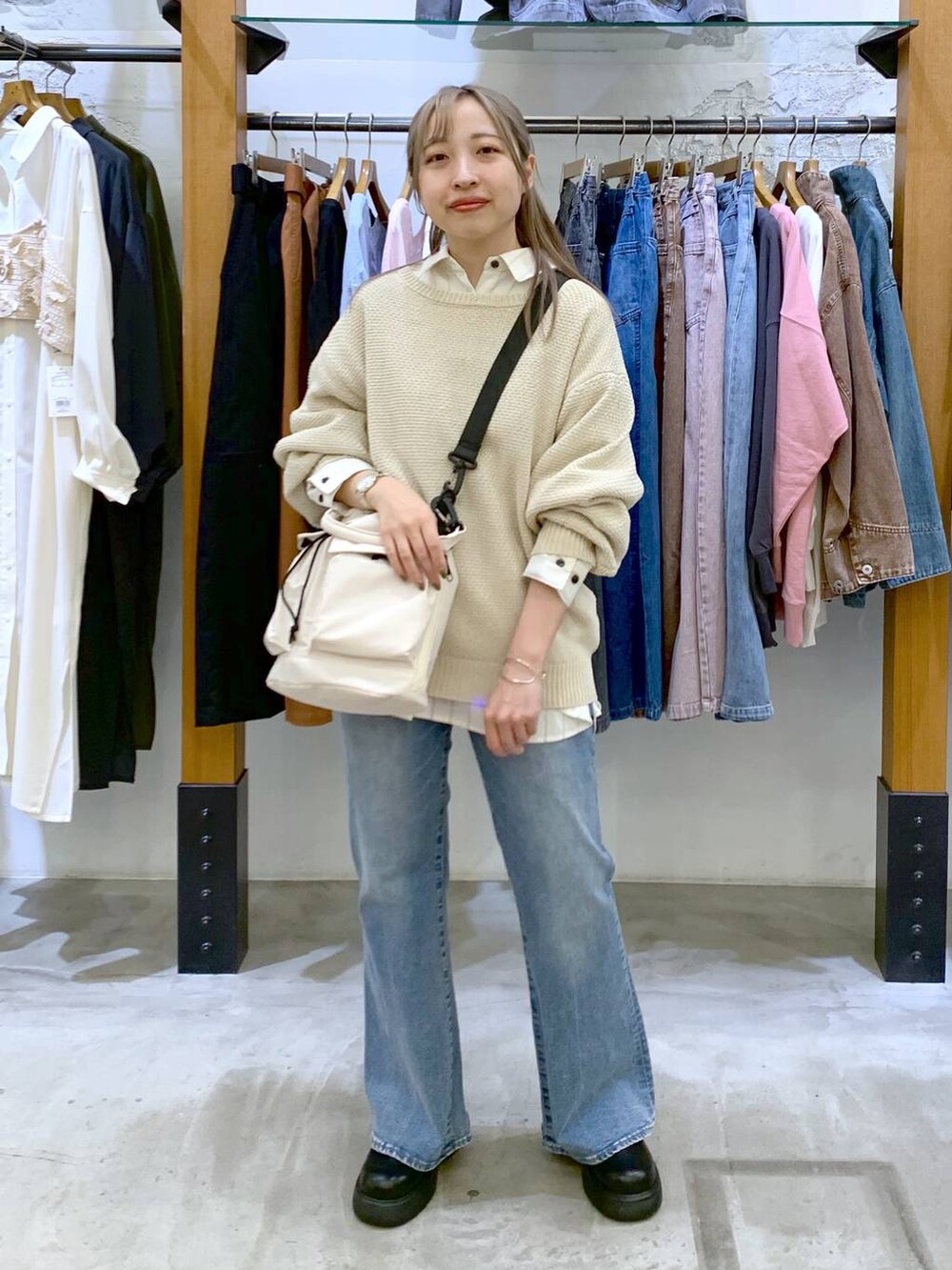 ホワイト系のショルダーバッグ、ホワイト系のニット/セーター、ブルー系のデニムパンツを着用したレディースの春コーディネートの4枚目の写真