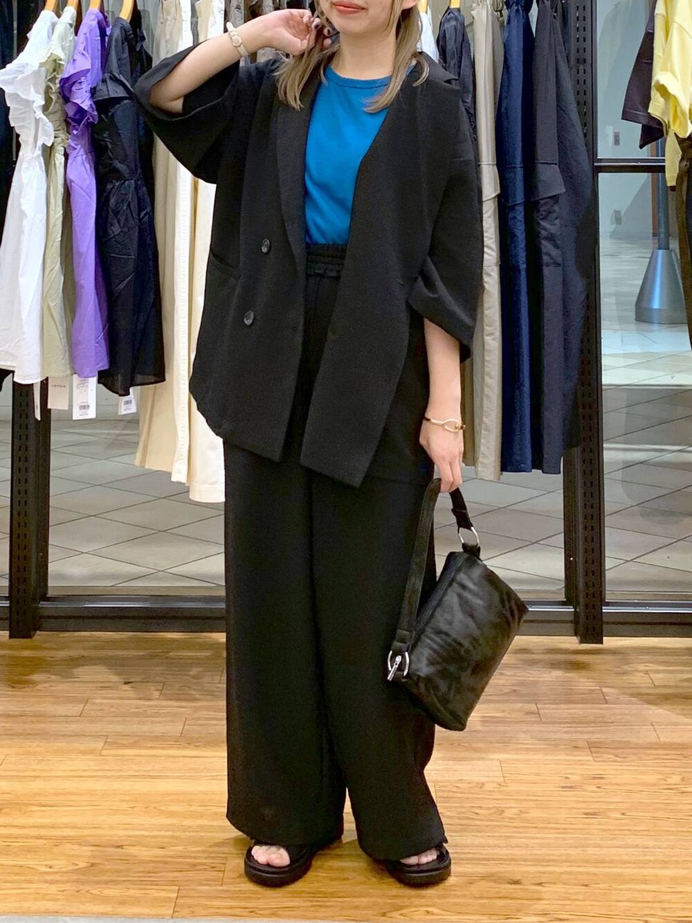 ブラック系のテーラードジャケット、ブルー系のタンクトップ、ブラック系のサンダルを着用したレディースの夏コーディネートの5枚目の写真