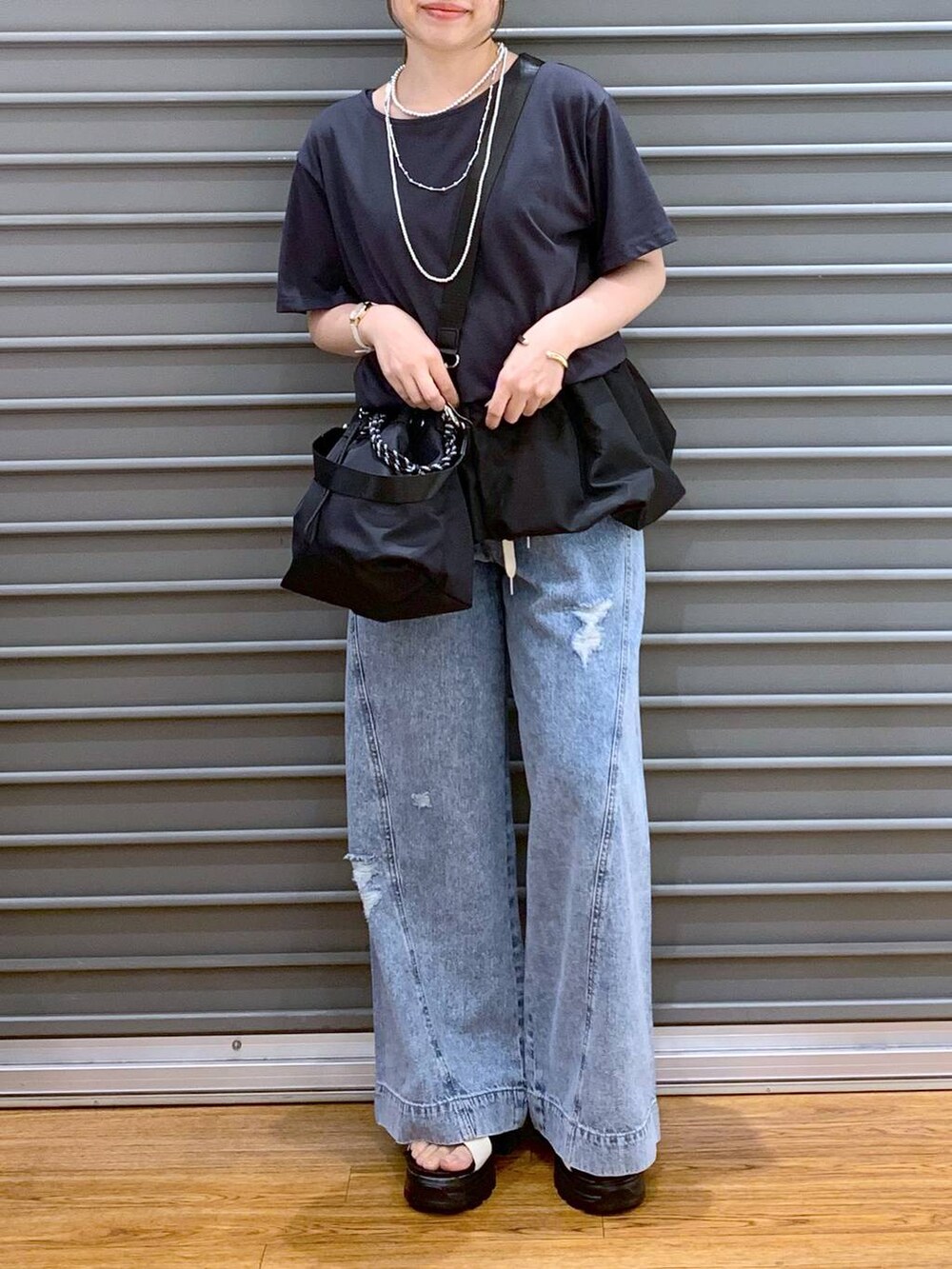 ブルー系のデニムパンツ、ホワイト系のサンダル、ブラック系のショルダーバッグを着用したレディースの秋コーディネートの5枚目の写真