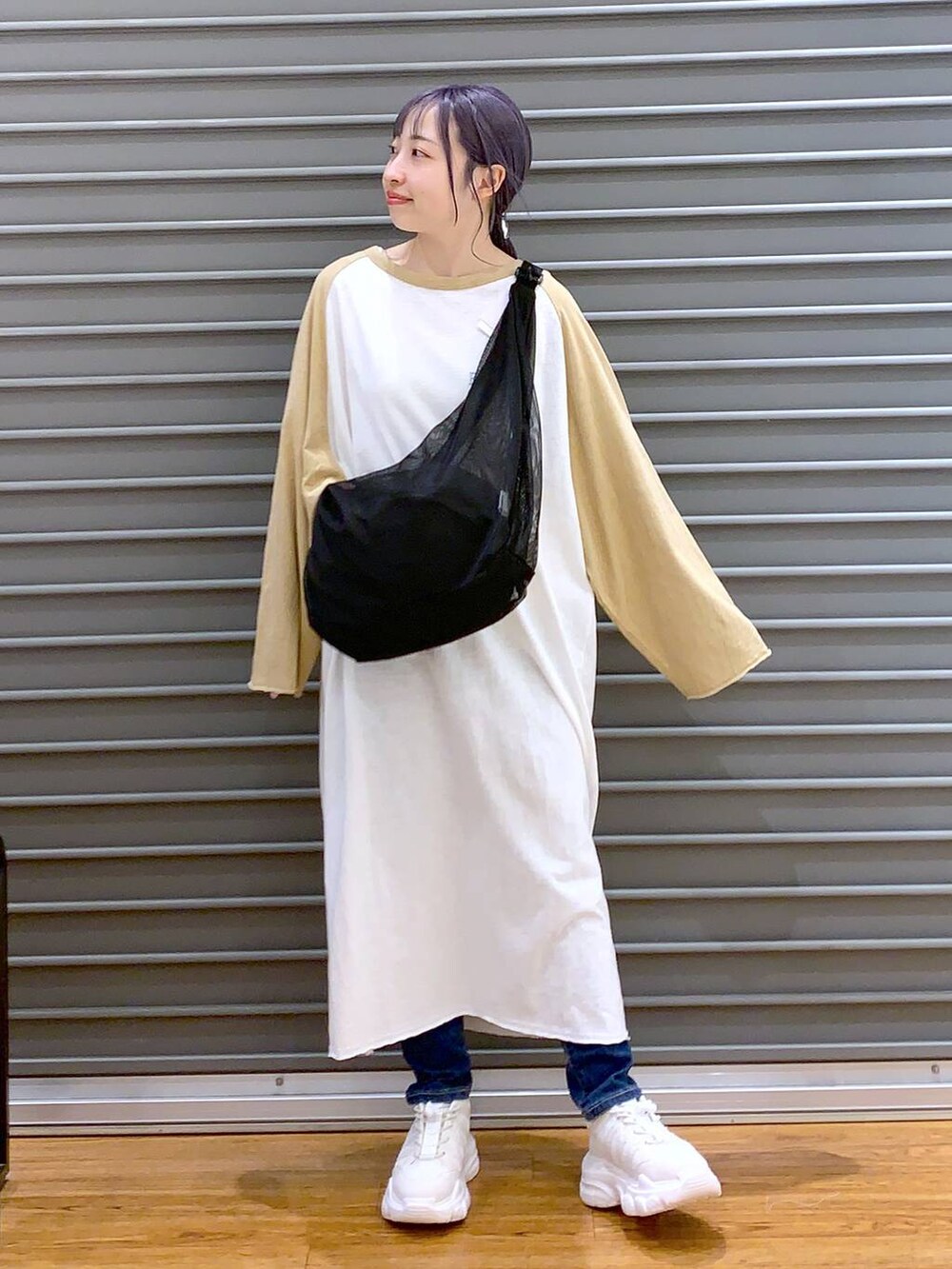 ベージュ系のワンピース、ホワイト系のスニーカー、ブルー系のデニムパンツを着用したレディースの春コーディネートの3枚目の写真