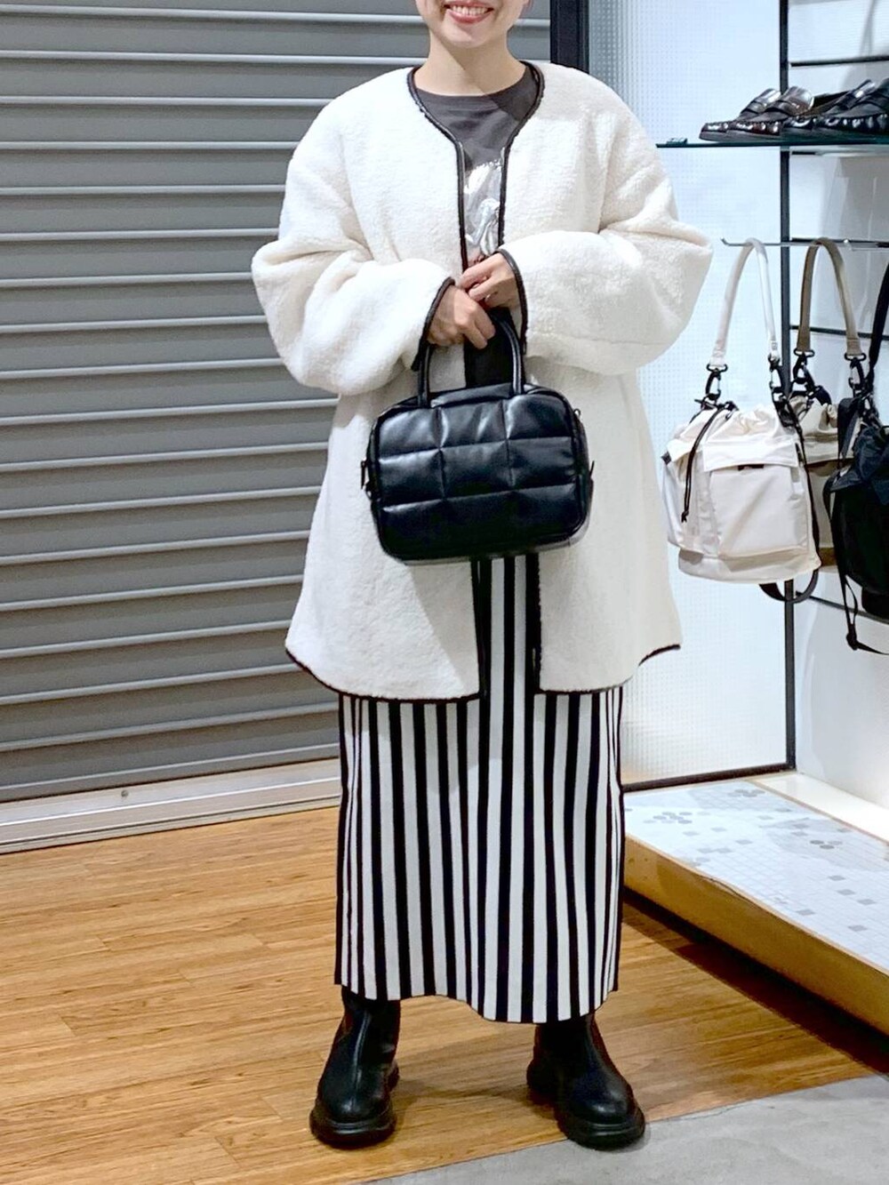 ブラック系のスカート、ホワイト系のその他アウター、ブラック系のボストンバッグを着用したレディースの秋コーディネートの5枚目の写真