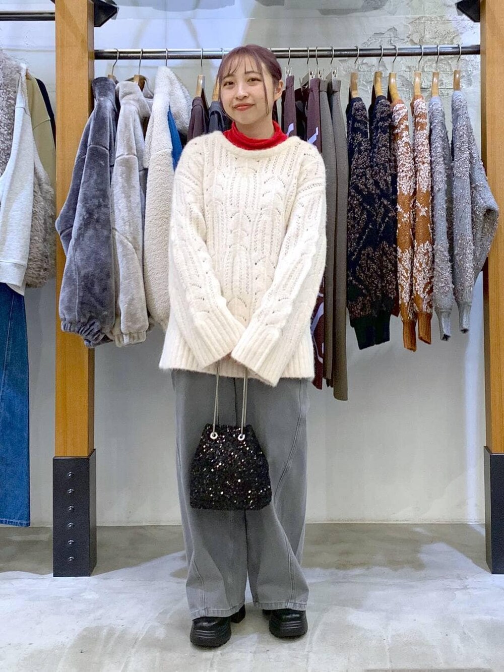 レッド系のTシャツ/カットソー、ブラック系のブーツ、ブラック系のショルダーバッグを着用したレディースの冬コーディネートの6枚目の写真
