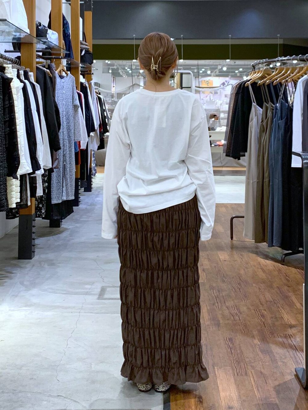 ブラック系のショルダーバッグ、ホワイト系のパンプス、イエロー系のスカートを着用したレディースの秋コーディネートの2枚目の写真