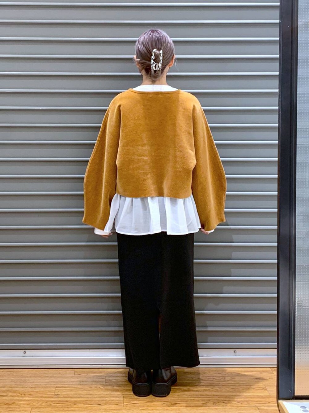 ブラック系のブーツ、ブラック系のスカート、ホワイト系のTシャツ/カットソーを着用したレディースの秋コーディネートの2枚目の写真