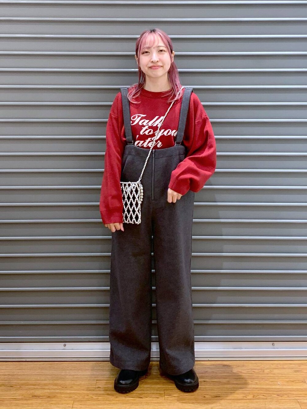 シルバー系のショルダーバッグ、レッド系のニット/セーター、ブラック系のブーツを着用したレディースの冬コーディネートの6枚目の写真