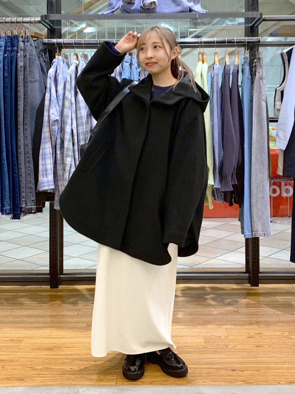 ブラック系のポンチョ、ホワイト系のスカート、ブラック系のショルダーバッグを着用したレディースの冬コーディネートの5枚目の写真