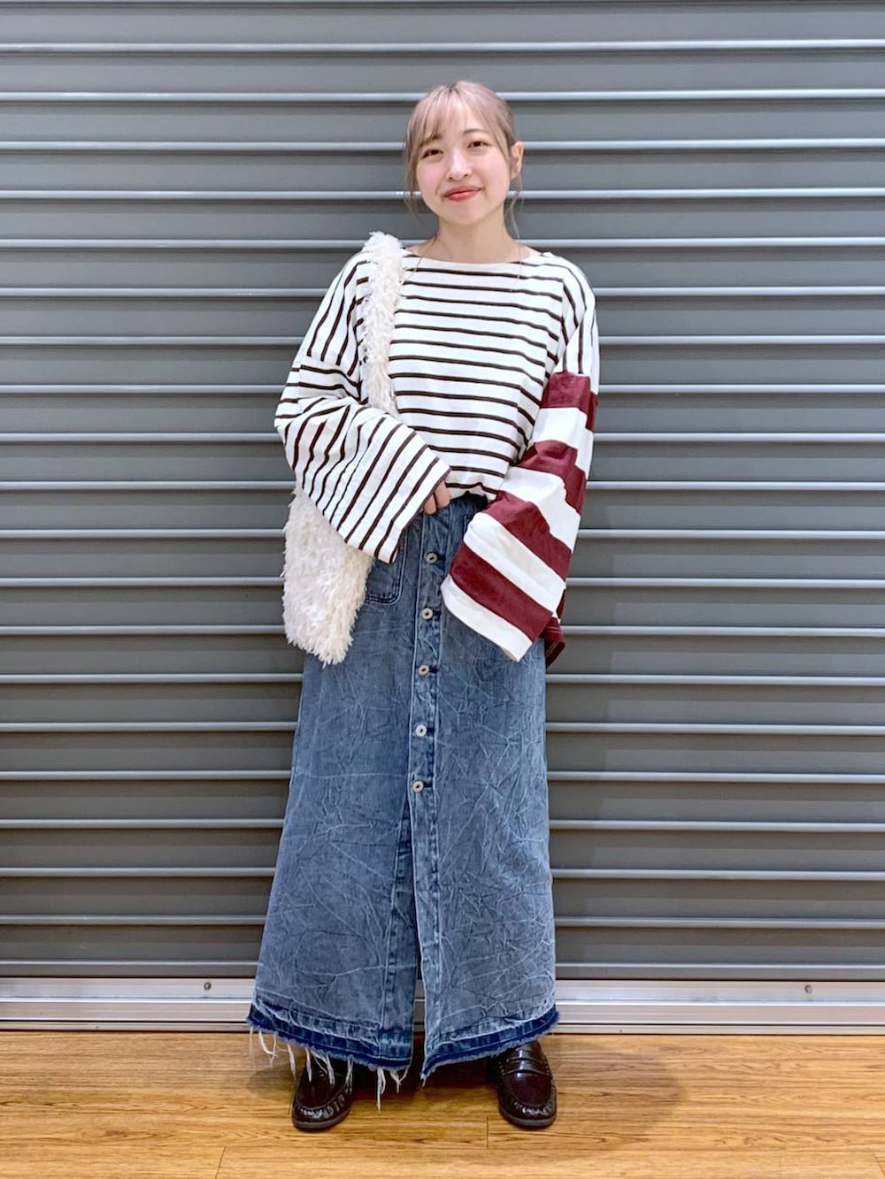 レッド系のTシャツ/カットソー、ブルー系のデニムスカート、ブラウン系のローファーを着用したレディースの秋コーディネートの4枚目の写真