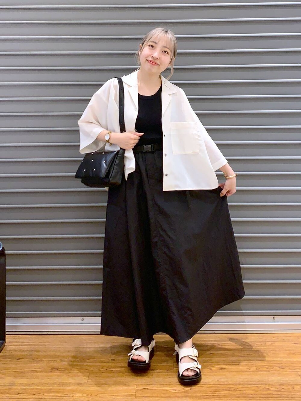 ブラック系のスカート、ブラック系のタンクトップ、ホワイト系のサンダルを着用したレディースの春コーディネートの3枚目の写真