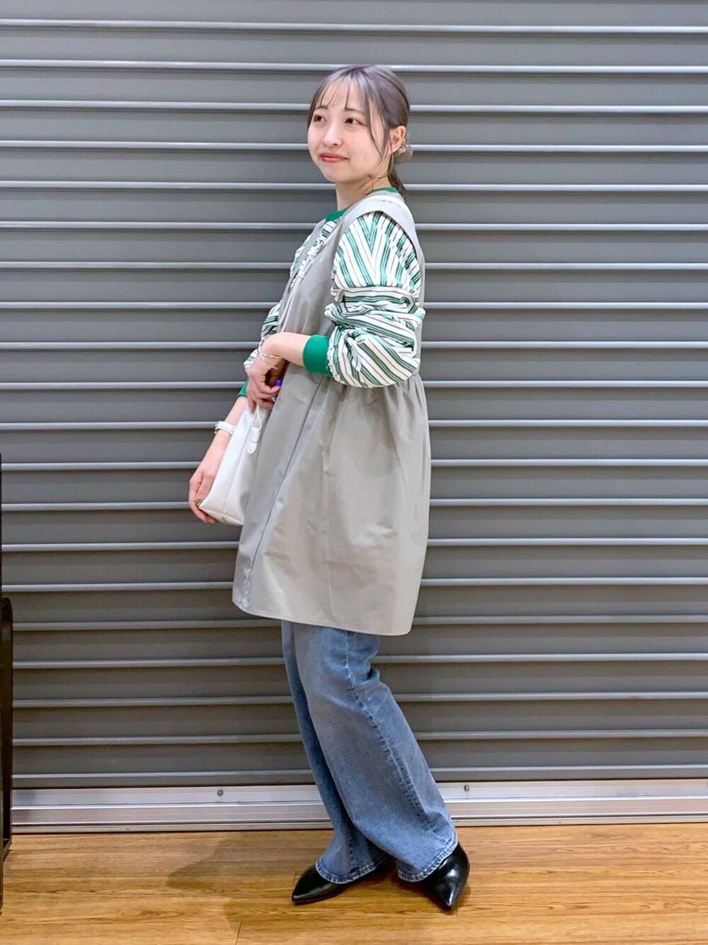 グリーン系のワンピース、ブルー系のデニムパンツ、ブラック系のパンプスを着用したレディースの春コーディネートの6枚目の写真