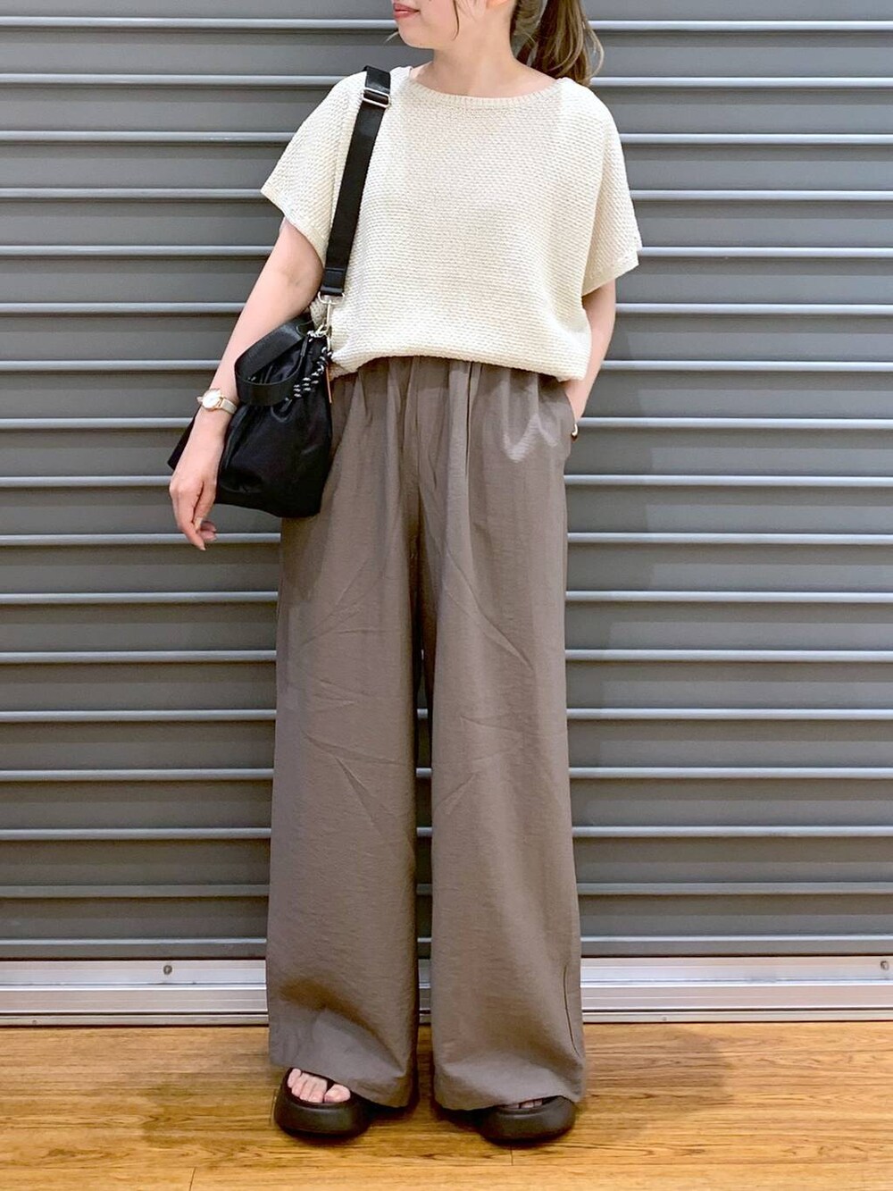 ホワイト系のニット/セーター、ブラウン系のサンダル、ブラック系のショルダーバッグを着用したレディースの夏コーディネートの4枚目の写真