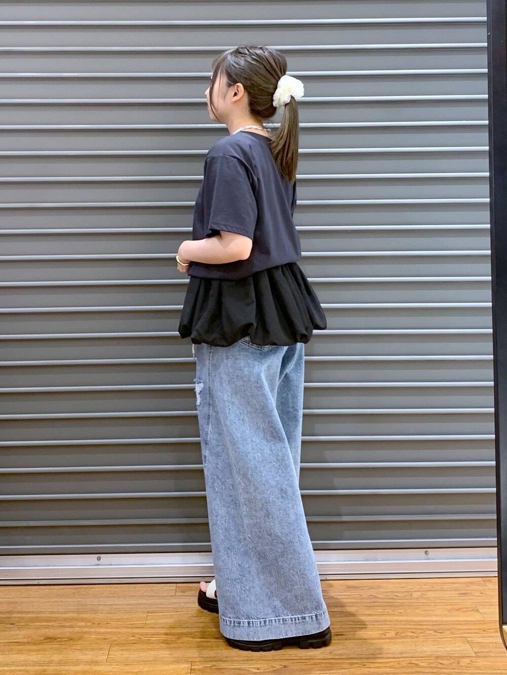 ブルー系のデニムパンツ、ホワイト系のサンダル、ブラック系のショルダーバッグを着用したレディースの秋コーディネートの3枚目の写真