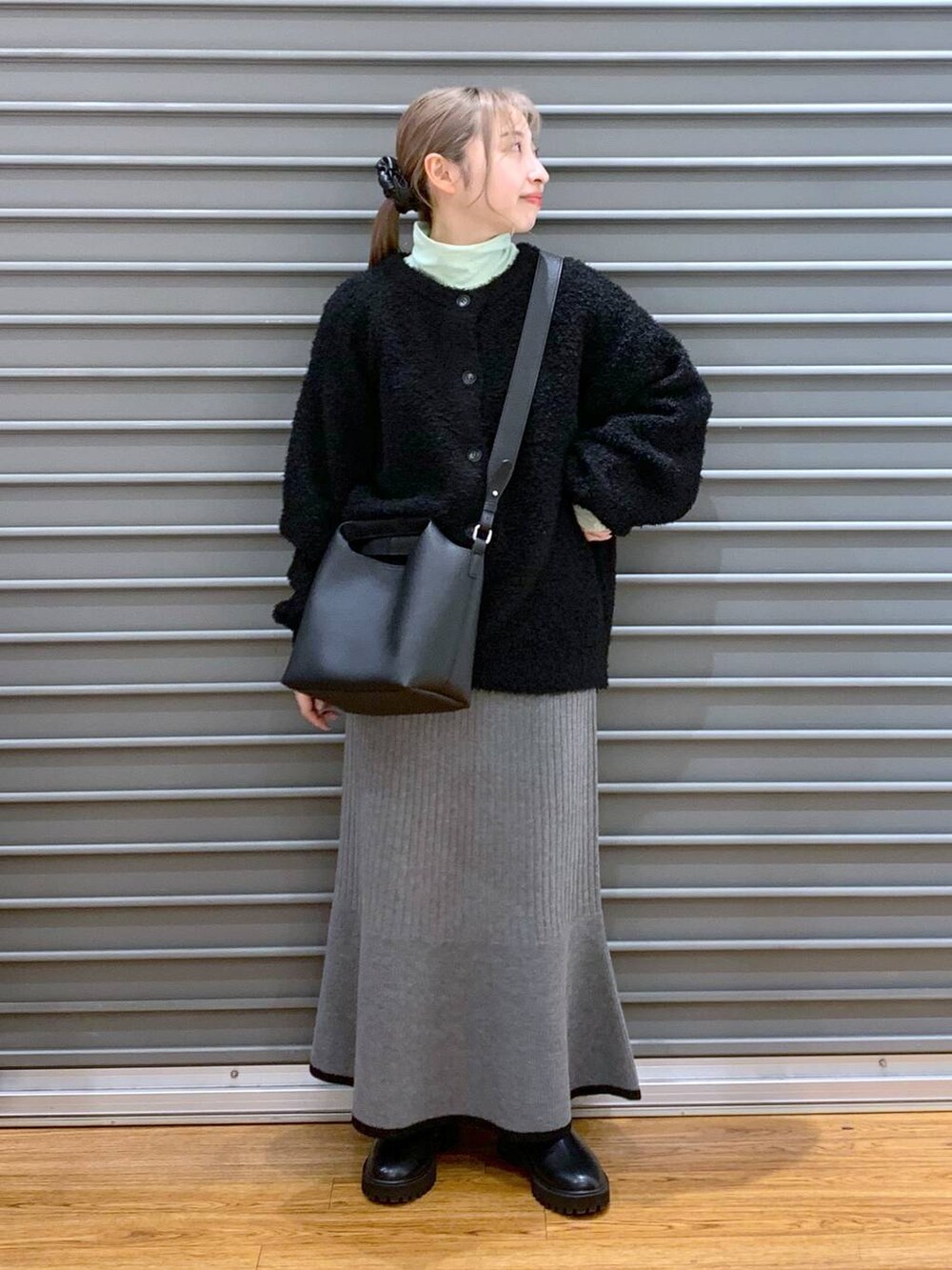 ブラック系のブーツ、ブラック系のワンピース、グリーン系のTシャツ/カットソーを着用したレディースの冬コーディネートの6枚目の写真