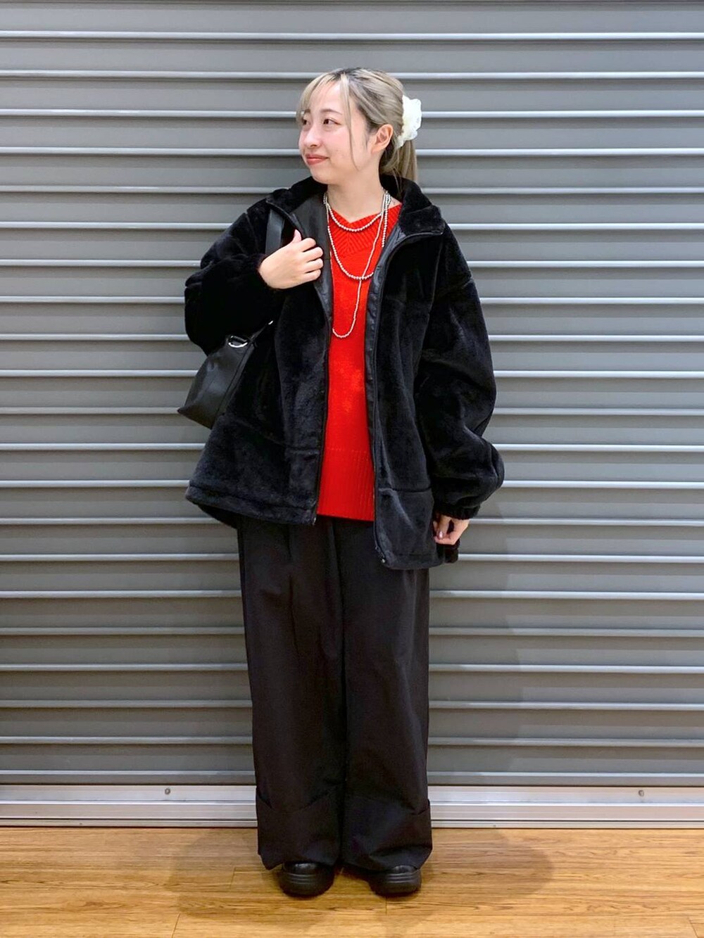 レッド系のニット/セーター、ブラック系のショルダーバッグ、ブラック系のブーツを着用したレディースの冬コーディネートの6枚目の写真