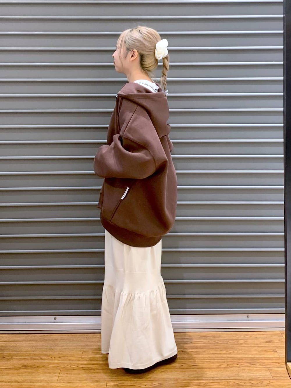 シルバー系のショルダーバッグ、ホワイト系のスカート、ブラウン系のパーカーを着用したレディースの秋コーディネートの3枚目の写真