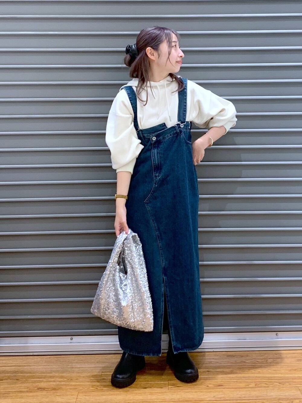 ブラック系のブーツ、ブルー系のジャンパースカート、ホワイト系のニット/セーターを着用したレディースの秋コーディネートの4枚目の写真