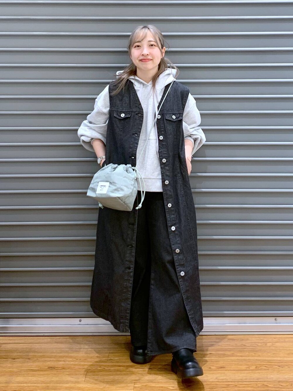 グレー系のパーカー、ブラック系のデニムパンツ、グリーン系のショルダーバッグを着用したレディースの春コーディネートの6枚目の写真