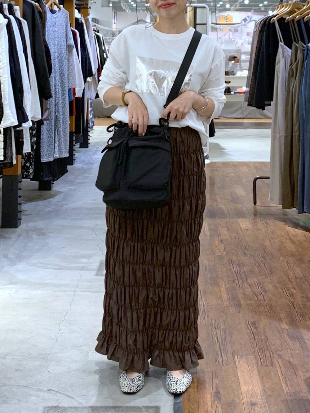 ブラック系のショルダーバッグ、ホワイト系のパンプス、イエロー系のスカートを着用したレディースの秋コーディネートの5枚目の写真