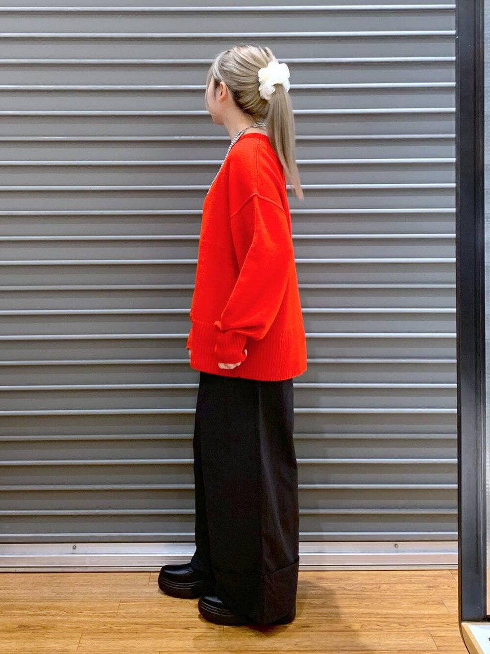 レッド系のニット/セーター、ブラック系のショルダーバッグ、ブラック系のブーツを着用したレディースの冬コーディネートの5枚目の写真