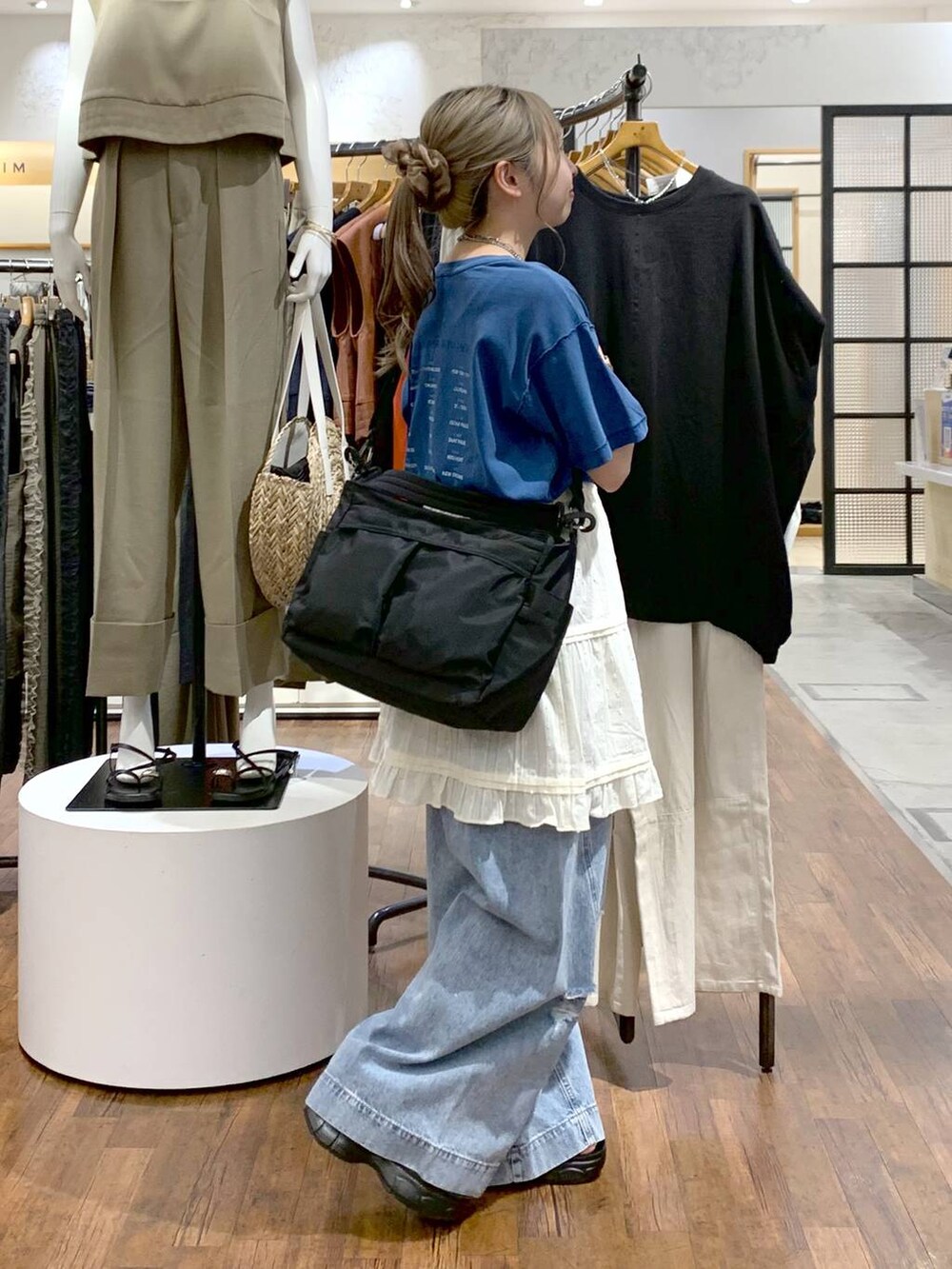 ブルー系のデニムパンツ、ブラック系のサンダル、ブラック系のショルダーバッグを着用したレディースの夏コーディネートの3枚目の写真
