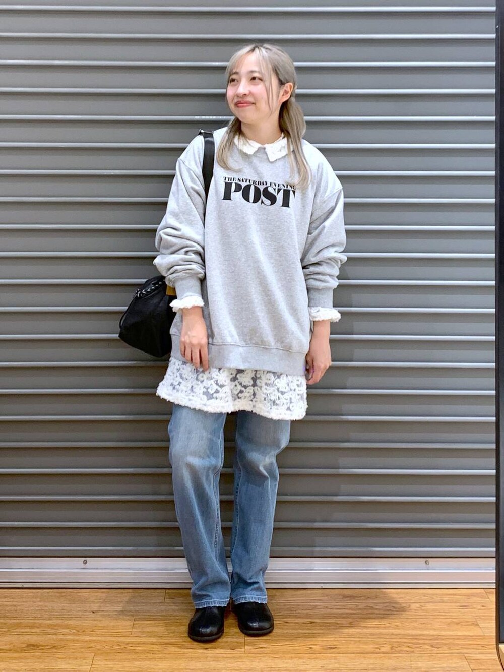ブラック系のショルダーバッグ、ブルー系のデニムパンツ、ブラック系のブーツを着用したレディースの冬コーディネートの4枚目の写真