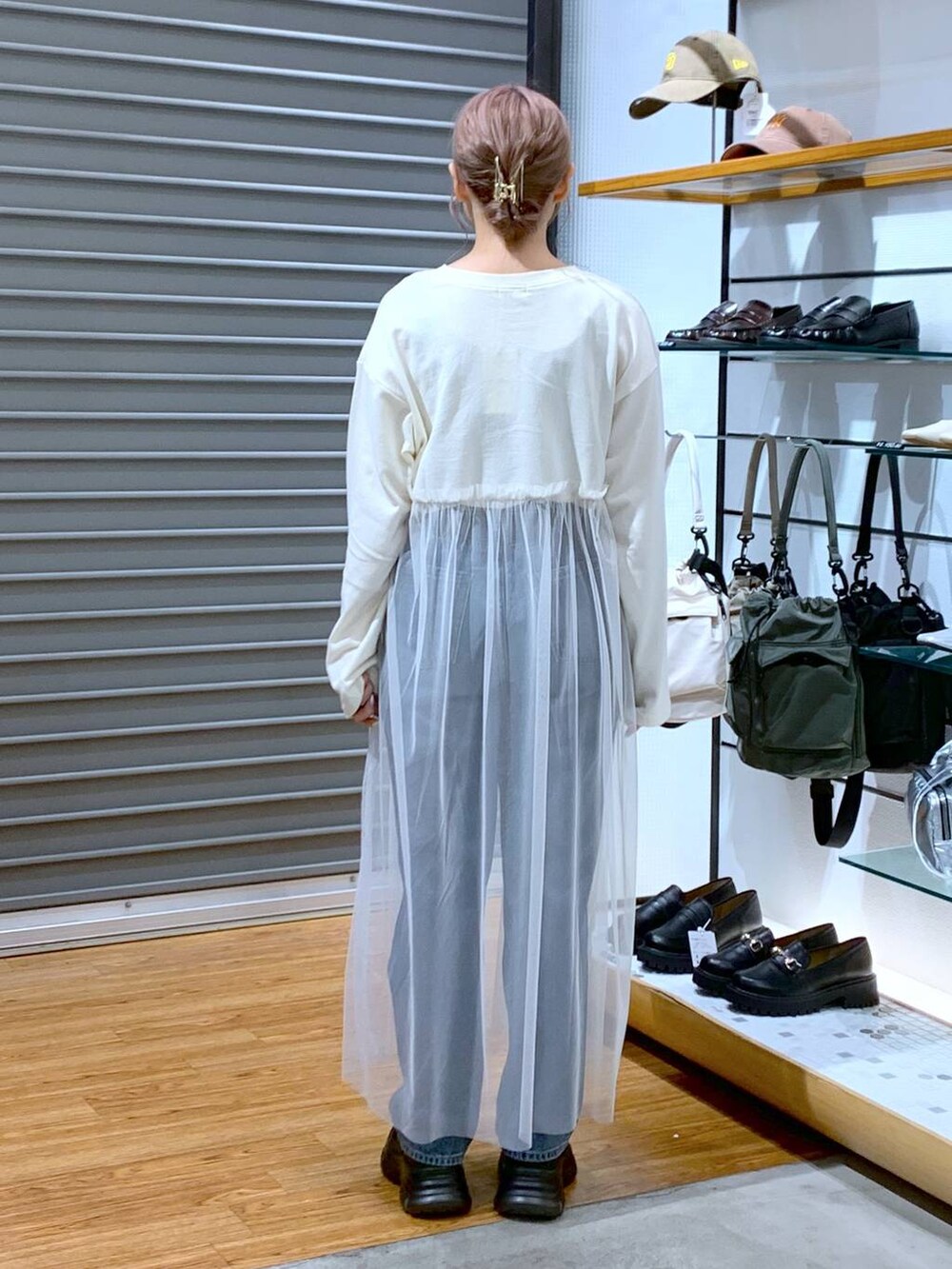 ブラック系のスニーカー、ブルー系のデニムパンツ、ブラック系のショルダーバッグを着用したレディースの秋コーディネートの2枚目の写真