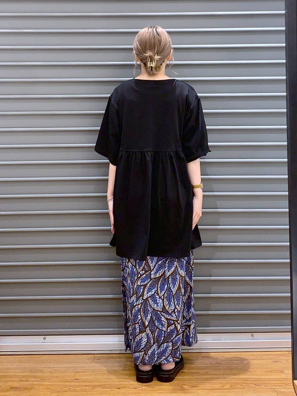 ブルー系のスカート、シルバー系のショルダーバッグ、ブラック系のサンダルを着用したレディースの夏コーディネートの2枚目の写真