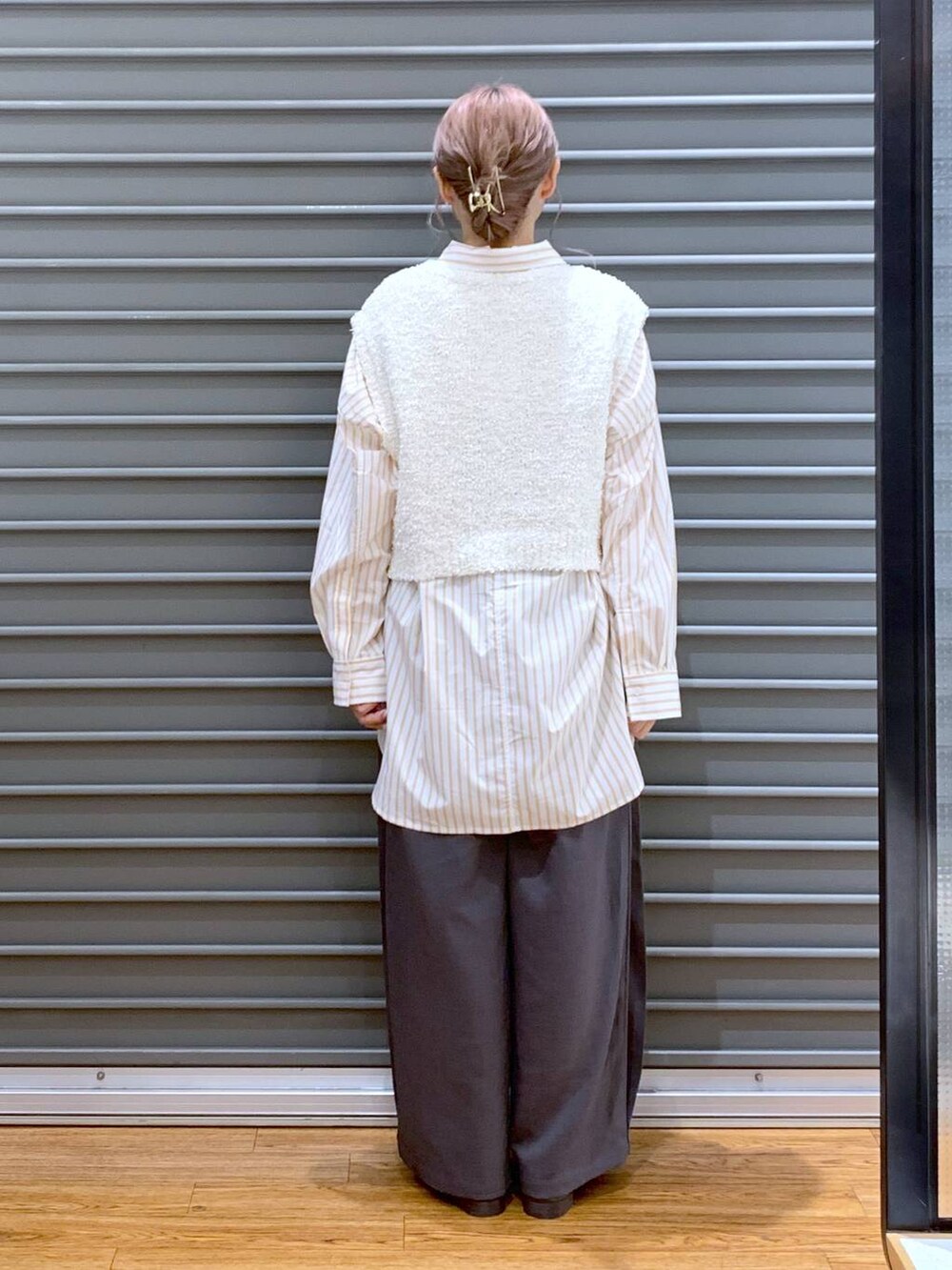 シルバー系のボストンバッグ、ホワイト系のベスト、オレンジ系のシャツ/ブラウスを着用したレディースの秋コーディネートの2枚目の写真