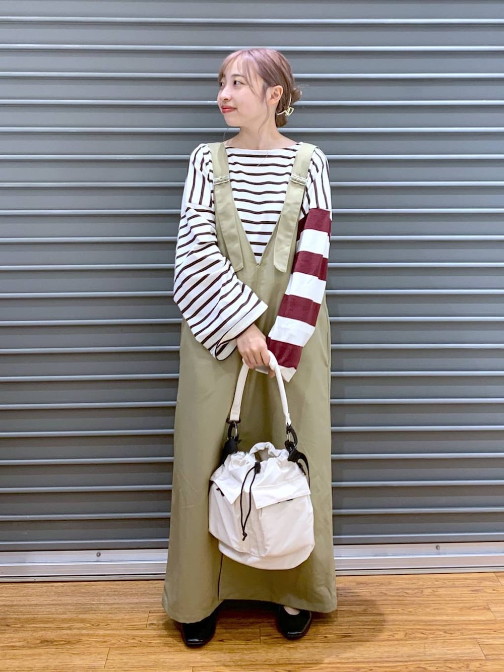 ホワイト系のショルダーバッグ、ブラック系のパンプス、ベージュ系のジャンパースカートを着用したレディースの秋コーディネートの3枚目の写真