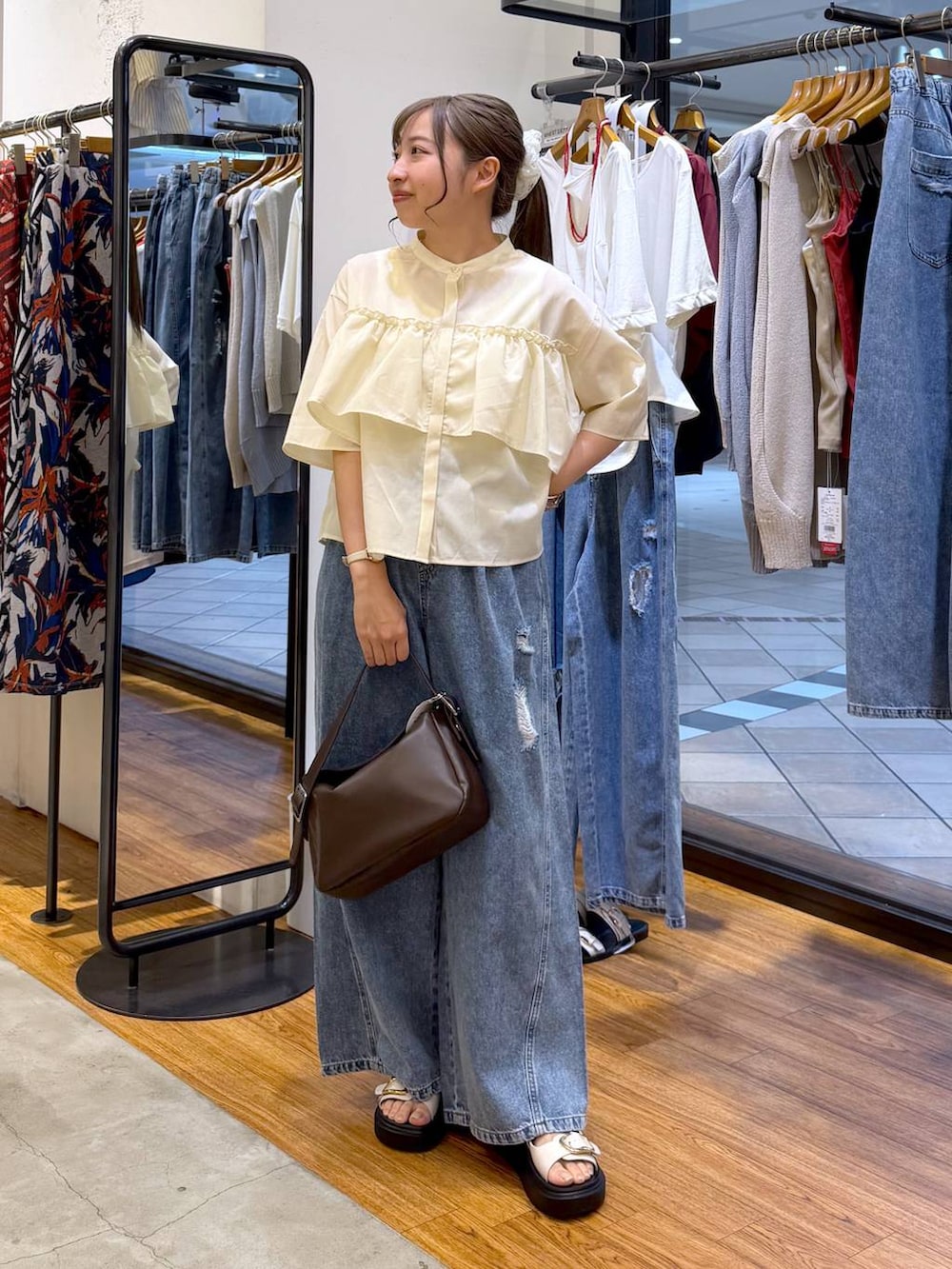 ブルー系のデニムパンツ、ホワイト系のサンダル、ブラウン系のショルダーバッグを着用したレディースの夏コーディネートの4枚目の写真