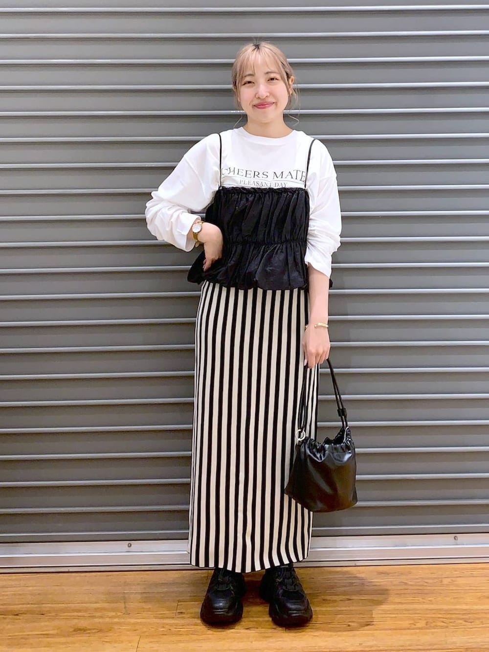 ブラック系のショルダーバッグ、ブラック系のスニーカー、ホワイト系のスカートを着用したレディースの春コーディネートの6枚目の写真