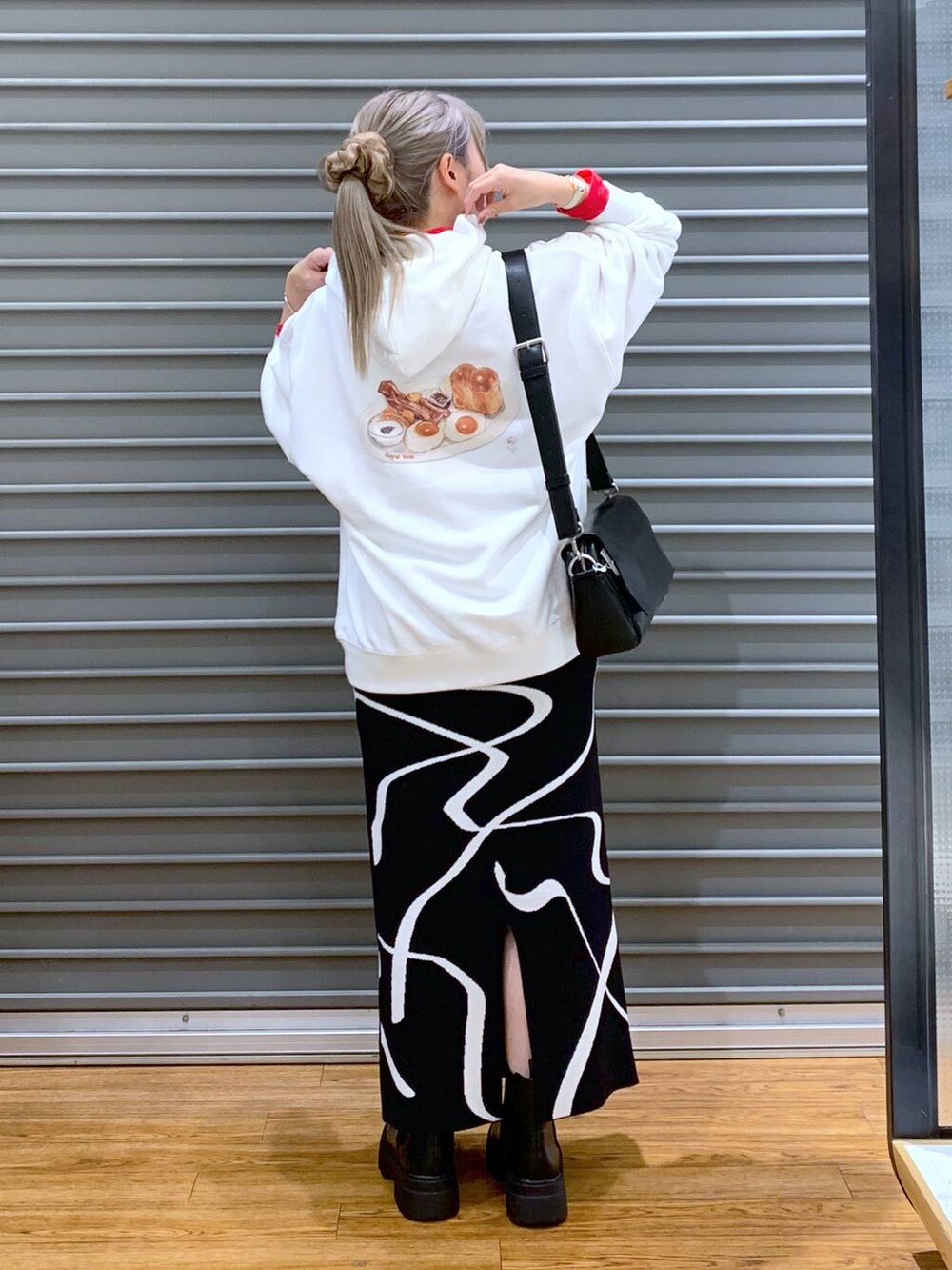 ブラック系のスカート、ブラック系のショルダーバッグ、ブラック系のブーツを着用したレディースの冬コーディネートの5枚目の写真