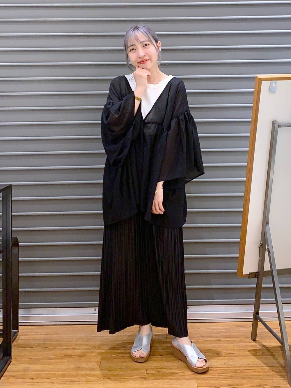 ブラック系のスカート、ブラック系のハンドバッグ、シルバー系のサンダルを着用したレディースの夏コーディネートの3枚目の写真