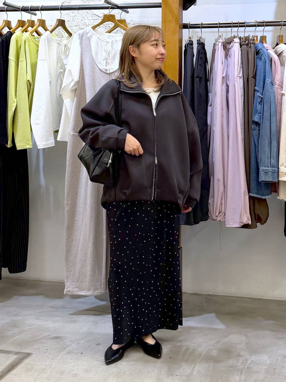 ブラック系のボストンバッグ、ブラック系のパンプス、グレー系のカーディガン/ボレロを着用したレディースの春コーディネートの5枚目の写真