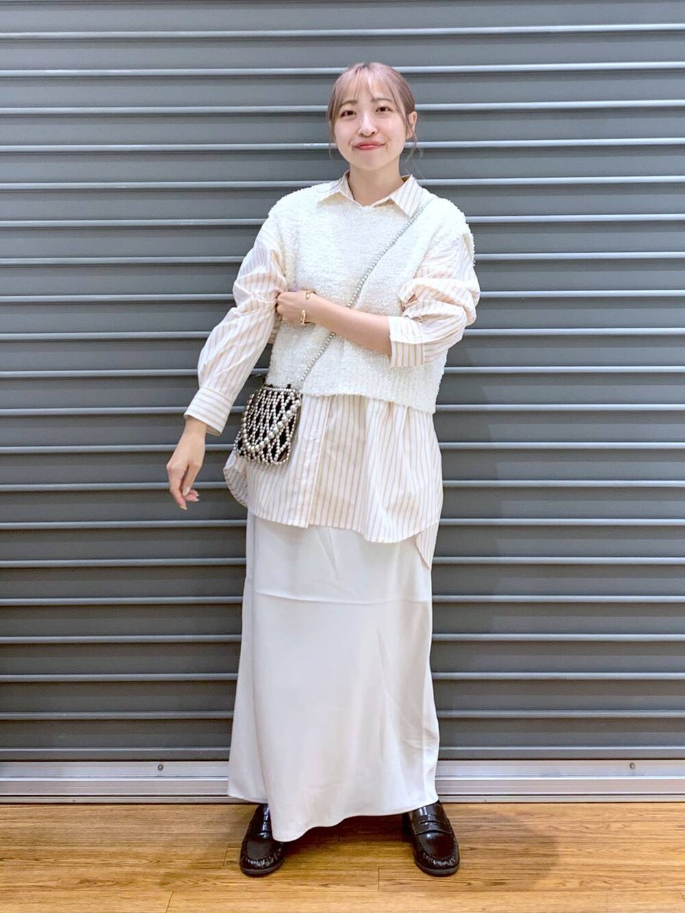 シルバー系のショルダーバッグ、ホワイト系のスカート、オレンジ系のシャツ/ブラウスを着用したレディースの秋コーディネートの3枚目の写真