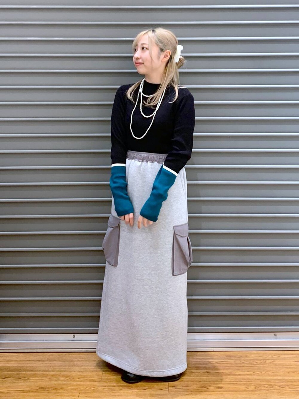 グレー系のブルゾン、ブラック系のニット/セーター、グレー系のスカートを着用したレディースの秋コーディネートの4枚目の写真