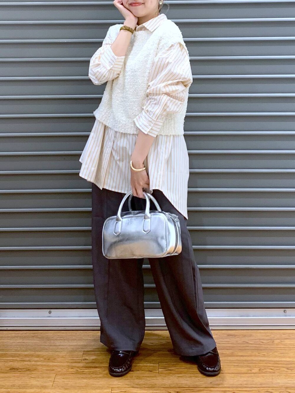 シルバー系のボストンバッグ、ホワイト系のベスト、オレンジ系のシャツ/ブラウスを着用したレディースの秋コーディネートの4枚目の写真
