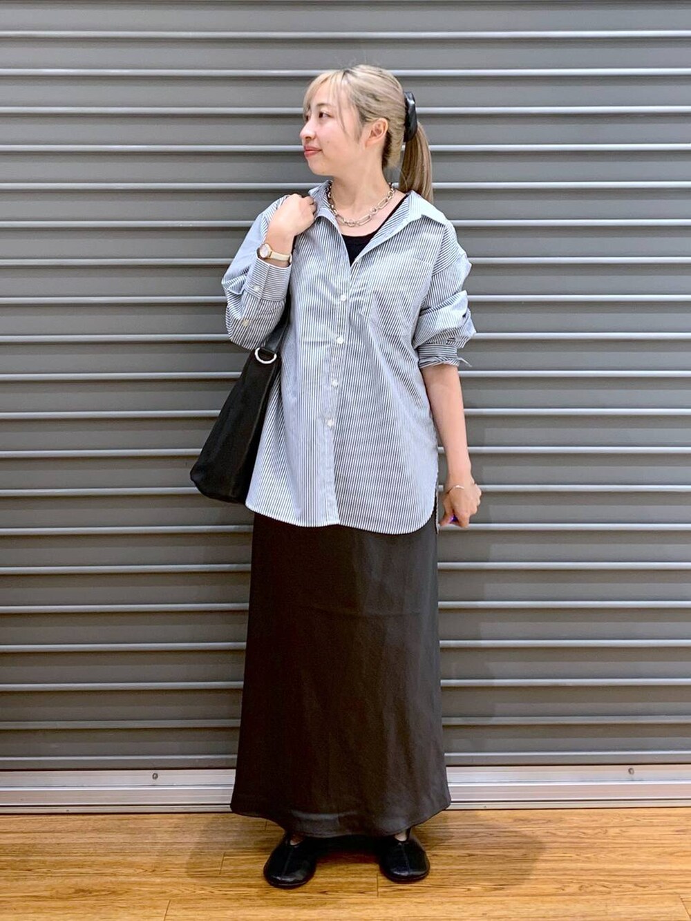 グレー系のスカート、ブラック系のショルダーバッグ、ブラック系のパンプスを着用したレディースの秋コーディネートの5枚目の写真
