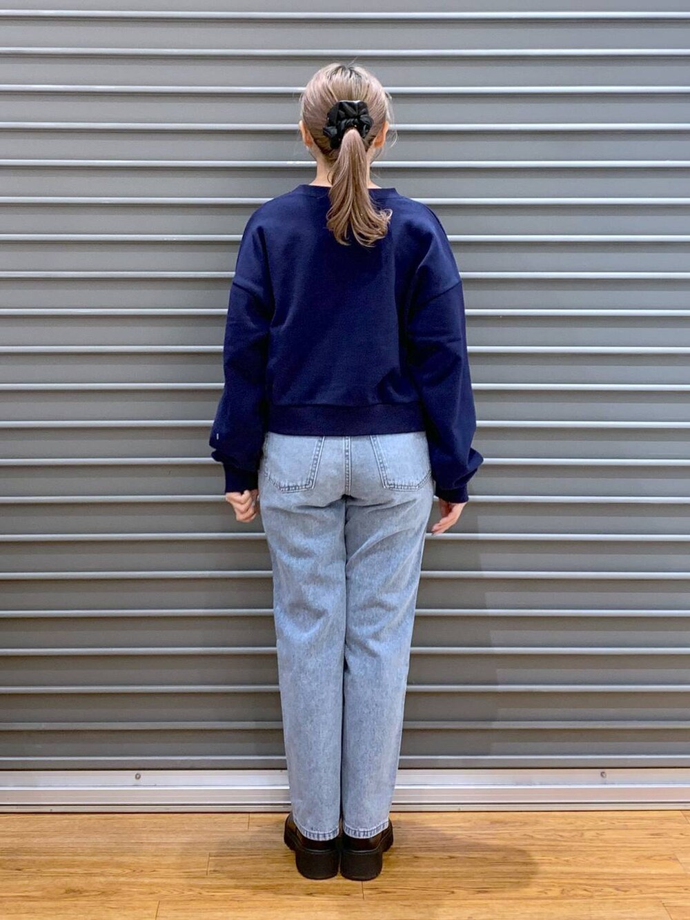 ブラック系のショルダーバッグ、ブルー系のデニムパンツ、ブラック系のブーツを着用したレディースの冬コーディネートの2枚目の写真