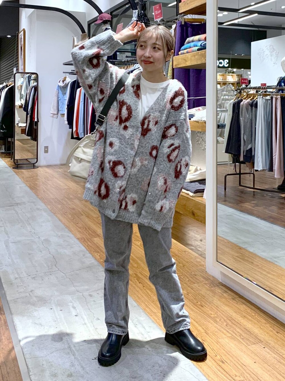 ブラック系のブーツ、グレー系のデニムパンツ、ホワイト系のショルダーバッグを着用したレディースの秋コーディネートの5枚目の写真