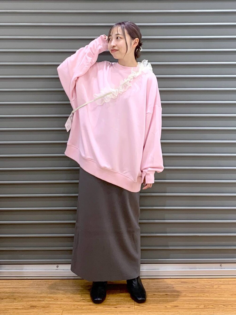 グレー系のスカート、ブラック系のブーツ、ピンク系のスウェットを着用したレディースの冬コーディネートの3枚目の写真