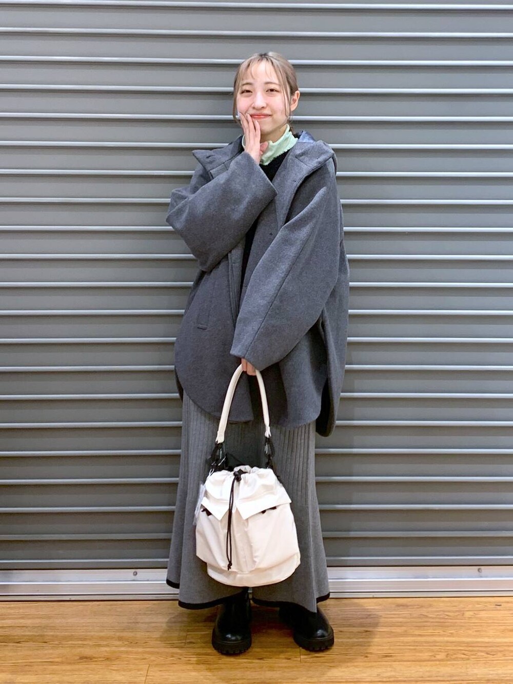 ホワイト系のショルダーバッグ、グレー系のポンチョ、ブラック系のブーツを着用したレディースの冬コーディネートの5枚目の写真