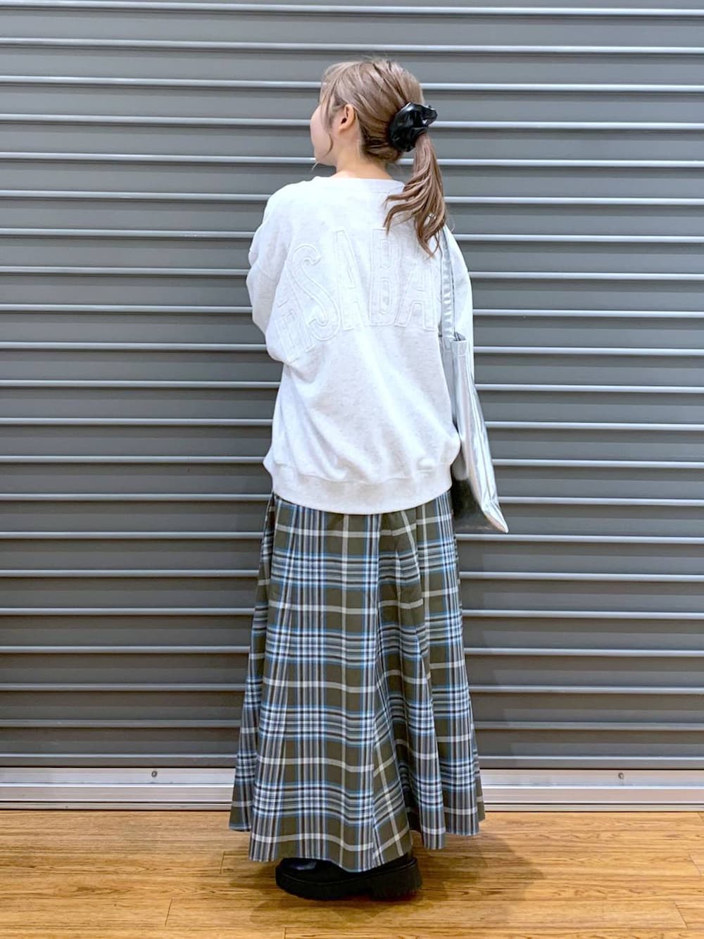 シルバー系のトートバッグ、ブラック系のブーツ、グリーン系のスカートを着用したレディースの冬コーディネートの6枚目の写真