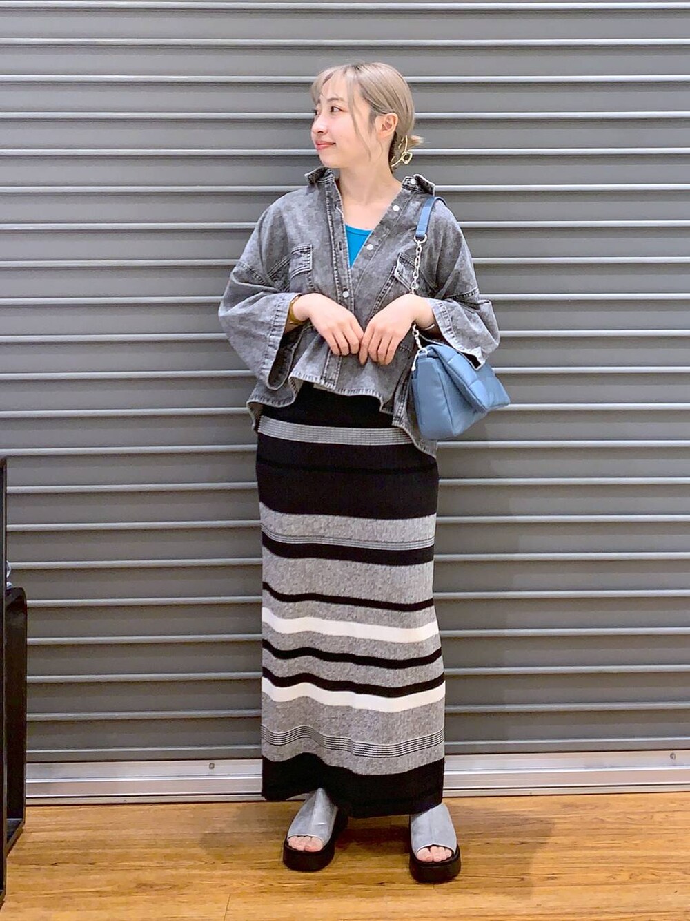 ブルー系のショルダーバッグ、ブラック系のシャツ/ブラウス、グレー系のサンダルを着用したレディースの春コーディネートの3枚目の写真